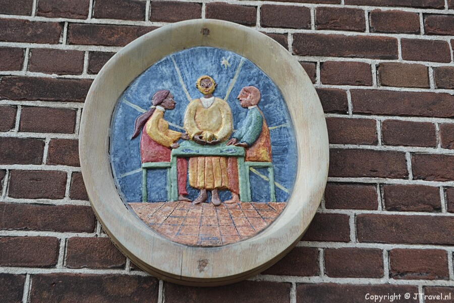 Het reliëf van de Emmaüsgangers naast de ingang van het parochiehuis van R.K.-kerk Joannes de Doper in Hoofddorp